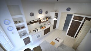 Una cocina con gabinetes blancos, una estufa y un fregadero. Hay platos azules y blancos en la pared.