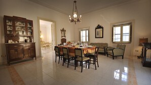 Un comedor amplio con una gran mesa dispuesta para seis personas, rodeada de sillas. Se ve un aparador de madera con puertas de vidrio a la izquierda.