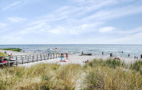 A beach with a wooden pier, people walking, and the ocean in the background. - Cozy home in Grenaa with kitchen (Grenaa)