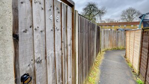 Un étroit sentier bordé de clôtures en bois portant les numéros 46 et 47.