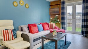 Un salon comprenant un canapé, des fauteuils, une table basse et une porte-fenêtre coulissante donnant sur un jardin.