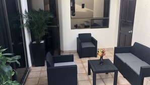 A patio area with wicker furniture, a potted plant, and a mirror on the wall. - 3 Bedroom Villa Oceanside in Hermosa Palms (Playa Hermosa)