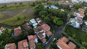 An aerial view of a coastal residential area with houses, a swimming pool, and a beach. - 3 Bedroom Villa Oceanside in Hermosa Palms (Playa Hermosa)