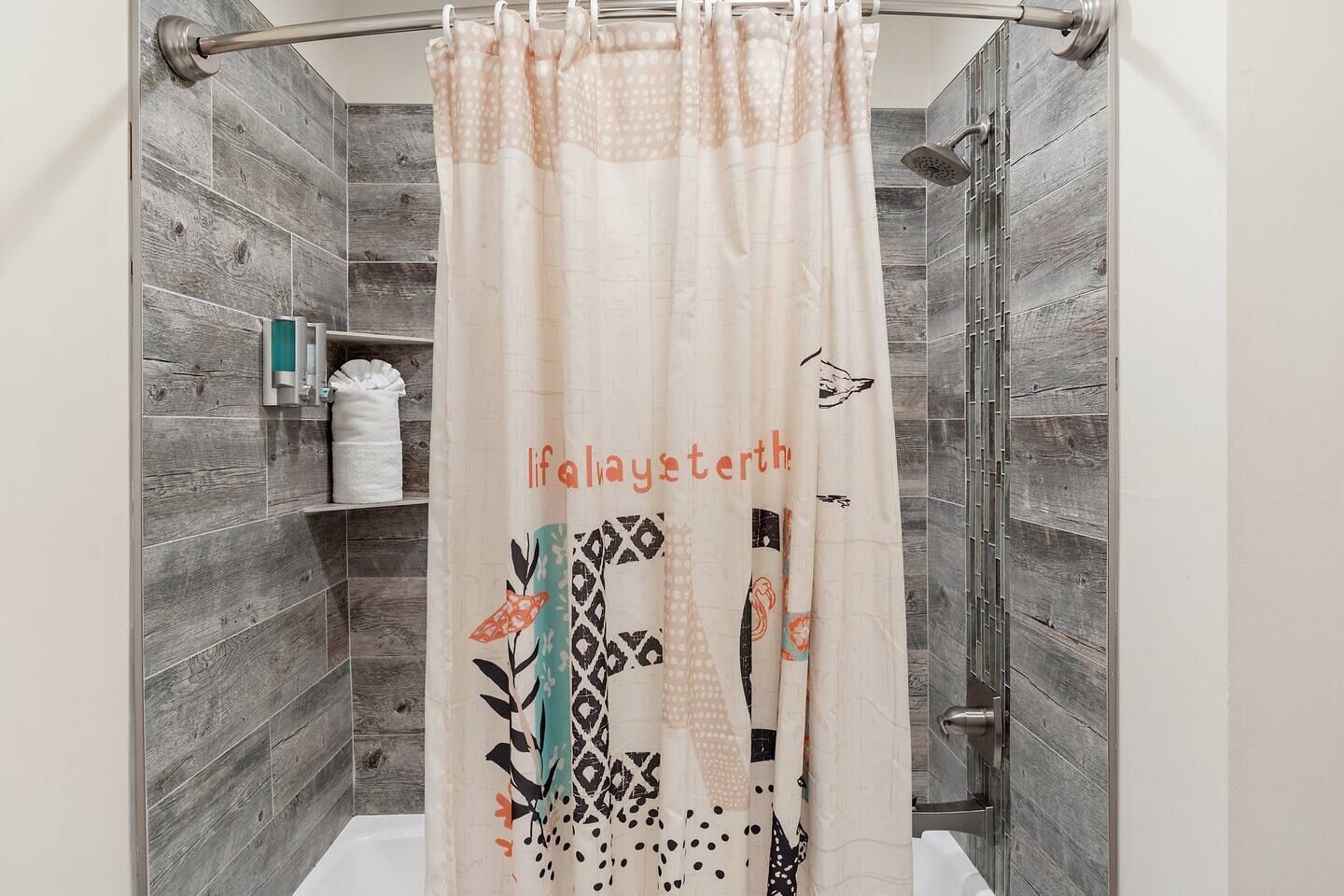 Una ducha con cortina color crema con estampado de pájaro y hojas, y el texto "lifalaysetherth".
