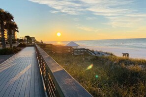 Un camí de fusta que condueix a una platja amb un capvespre de fons.