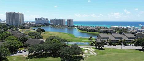 A coastal residential area with multiple high-rise buildings, a golf course, and a body of water.