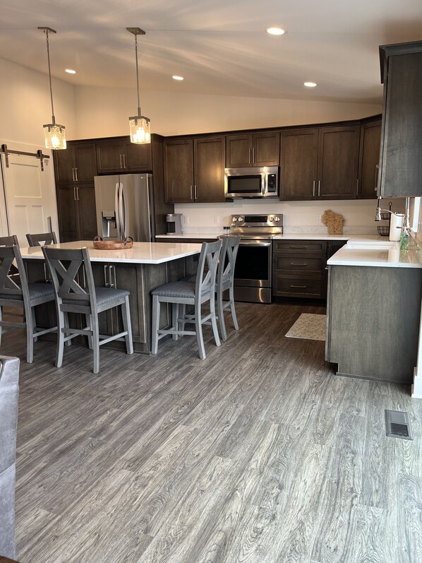 A modern kitchen with dark wood cabinets, stainless steel appliances, and a central island with seating.
