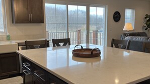 A modern kitchen with dark cabinets, a large island, and pendant lighting. - Beautiful, newly built 3rd floor Townhouse in historic Elkhart Lake, WI. (Plymouth)