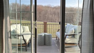 Une pièce dotée d’une porte-fenêtre coulissante donnant sur une terrasse extérieure avec des sièges blancs rembourrés et une pancarte indiquant : « ROAD AMERICA ELKHART LAKE ».