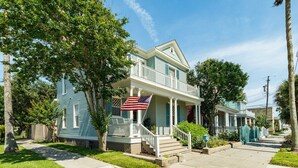 A two-story house with a porch and an American flag. - La Onda Azul - Luxe Retreat Steps to Seawall (Galveston)