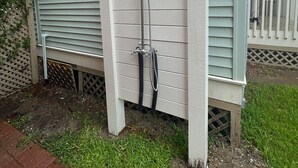 A residential property with a covered patio, a small window, and a hose attached to the exterior wall. - La Onda Azul - Luxe Retreat Steps to Seawall (Galveston)