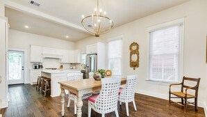 A spacious kitchen with white cabinetry, a wooden dining table, and a chandelier. - La Onda Azul - Luxe Retreat Steps to Seawall (Galveston)