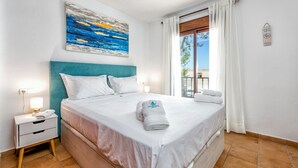 A hotel room with a bed, a nightstand, a lamp, a window with curtains, and a painting on the wall. - Gorgeous home in Marbella with kitchen (Marbella)