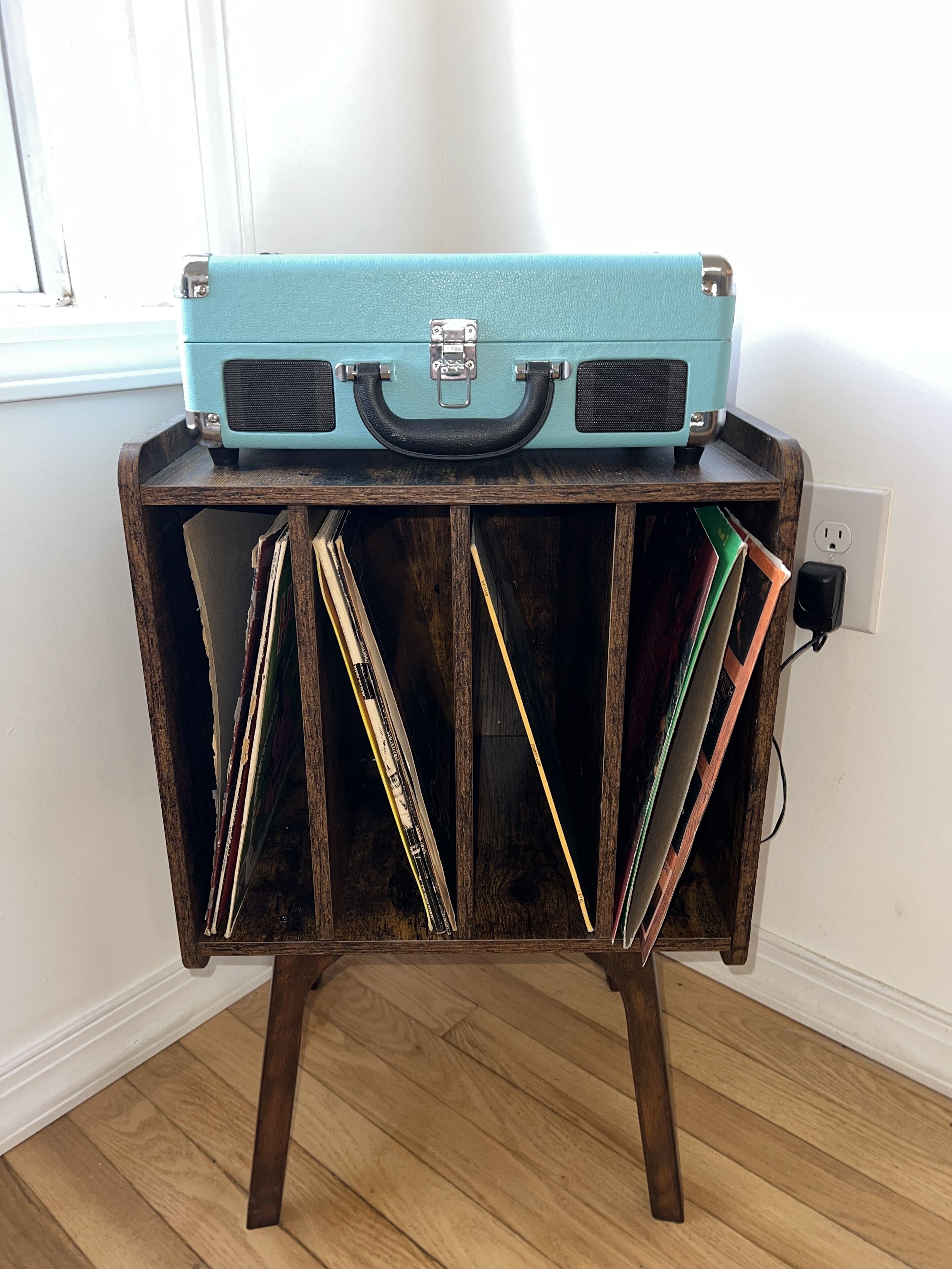 Een houten kast met een vintage koffer bovenop, waarin verschillende boeken en papieren zitten.