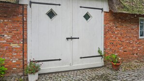 Una puerta de madera blanca con bisagras negras y un ventanal en forma de diamante.