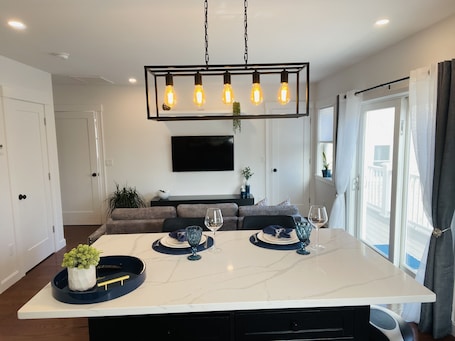 A modern kitchen with a marble countertop, a central island, and a hanging light fixture.