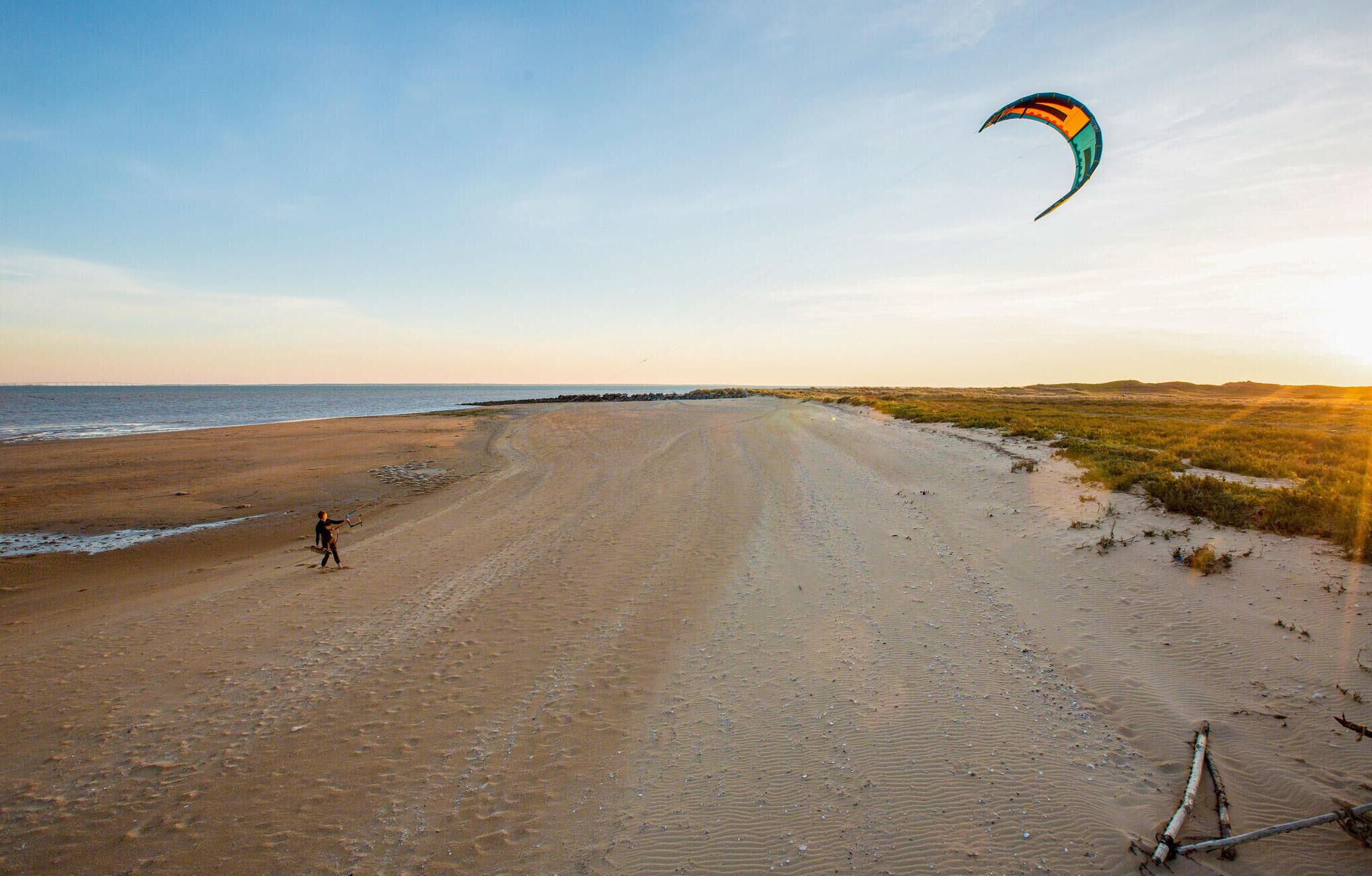 Une plage où une personne fait voler un cerf-volant.