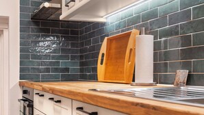 A kitchen with white cabinets, a wooden countertop, and a backsplash of dark blue tiles. - Charming Alpine Retreat – Just Minutes from Lake Bled and Lake Bohinj (Žirovnica)