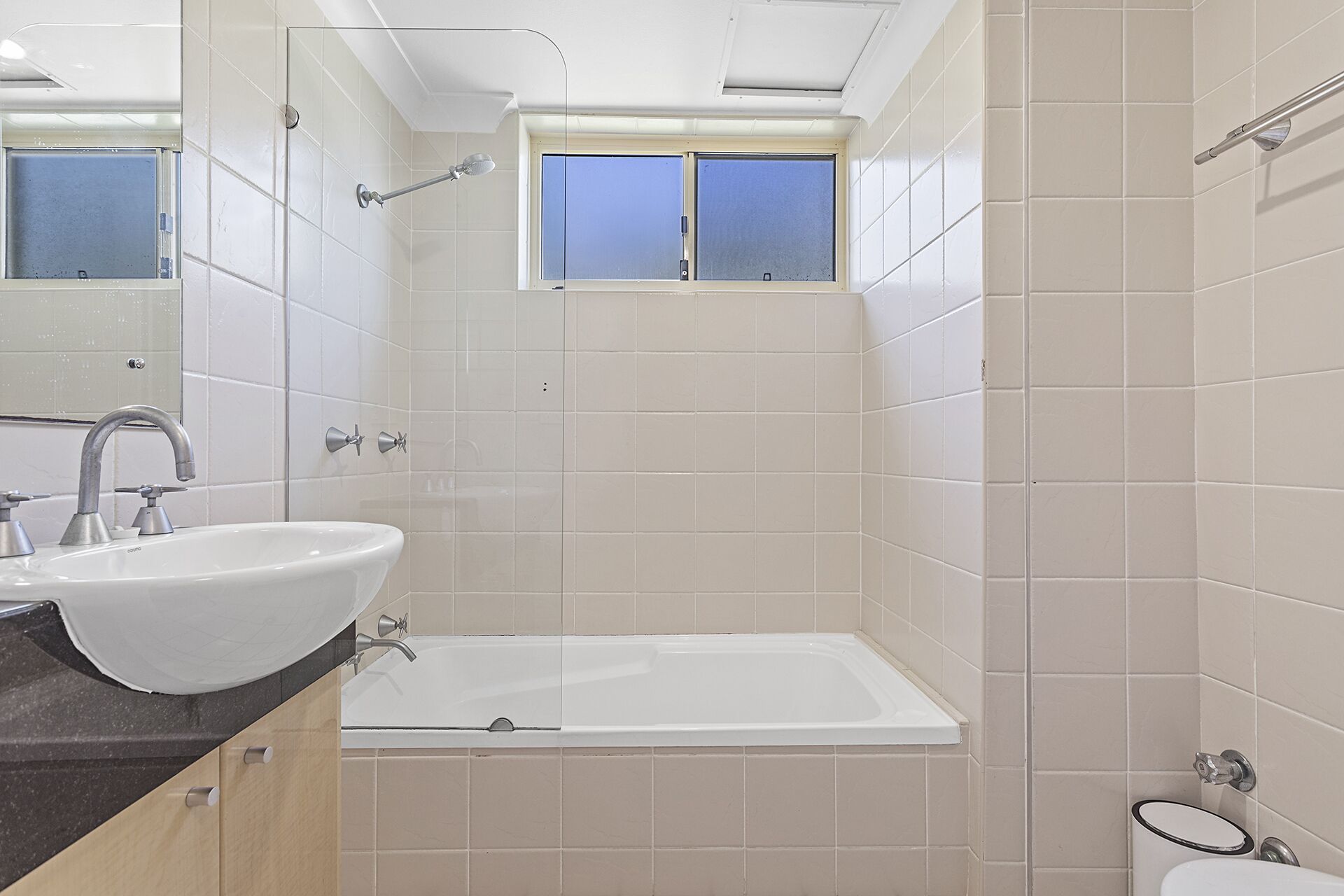 Un bagno moderno con un lavandino bianco, una vasca e una doccia.