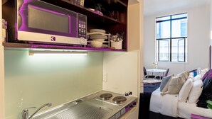 Uma cozinha compacta com micro-ondas, pia e área de refeições com mesa e cadeiras.
