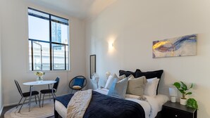 Quarto moderno com uma cama grande, mesas de cabeceira, uma pequena escrivaninha e uma cadeira.