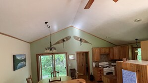 A spacious kitchen with wooden cabinets, a dining area with a wooden table and chairs, and a view of greenery through the windows. - Quiet place to land near Lake Michigan, Crystal Lake, Trails, Fishing, and more! (Frankfort)