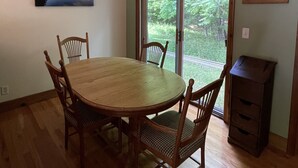 A dining room with a wooden table and chairs, a chandelier, and a large window with a view of greenery. - Quiet place to land near Lake Michigan, Crystal Lake, Trails, Fishing, and more! (Frankfort)