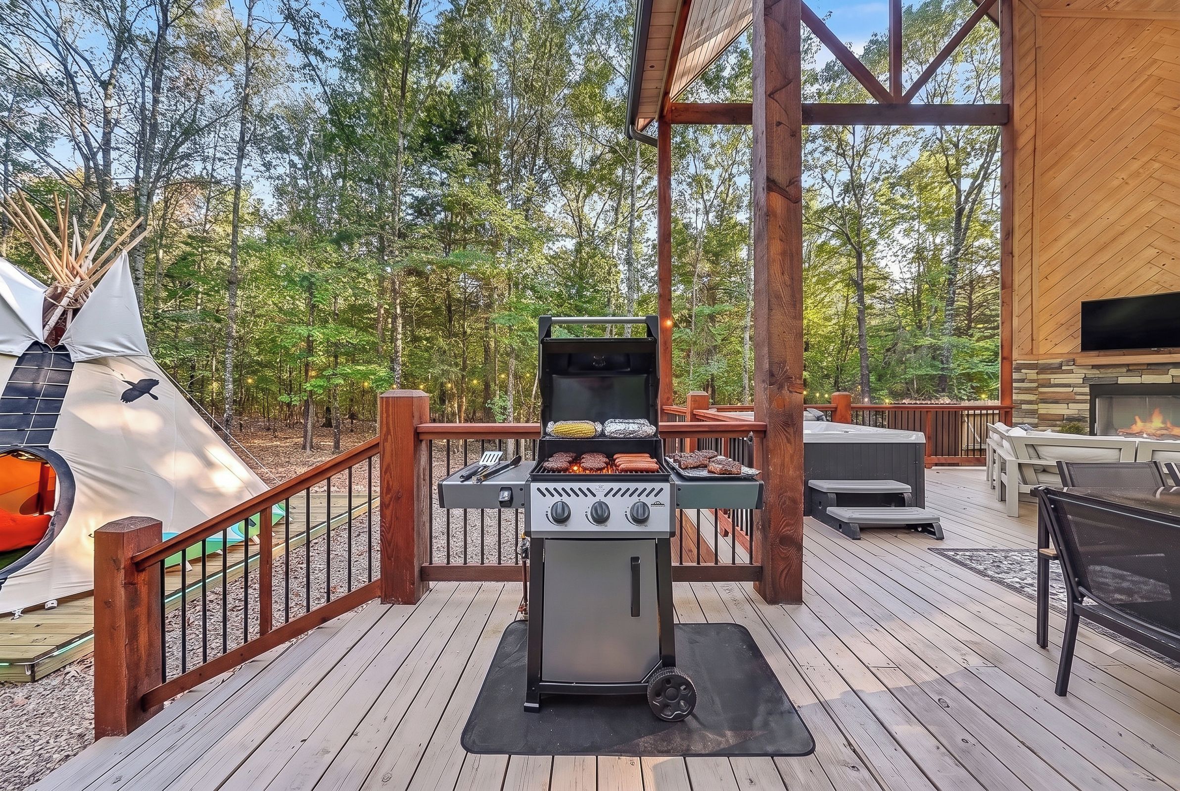 An outdoor deck with a grill, seating area, and a tent.