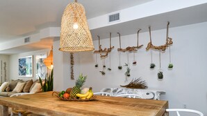 A dining area with a wooden table, white chairs, a woven pendant light, and wall-mounted planters with greenery. - Brand New Listing!  Beautiful - Upscale newly remodeled Modern Tropical Oasis! (Key Largo)