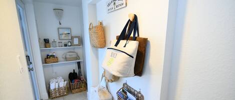 A hallway with a white wall, a sign reading 'Villa Palmera,' and various bags and baskets.