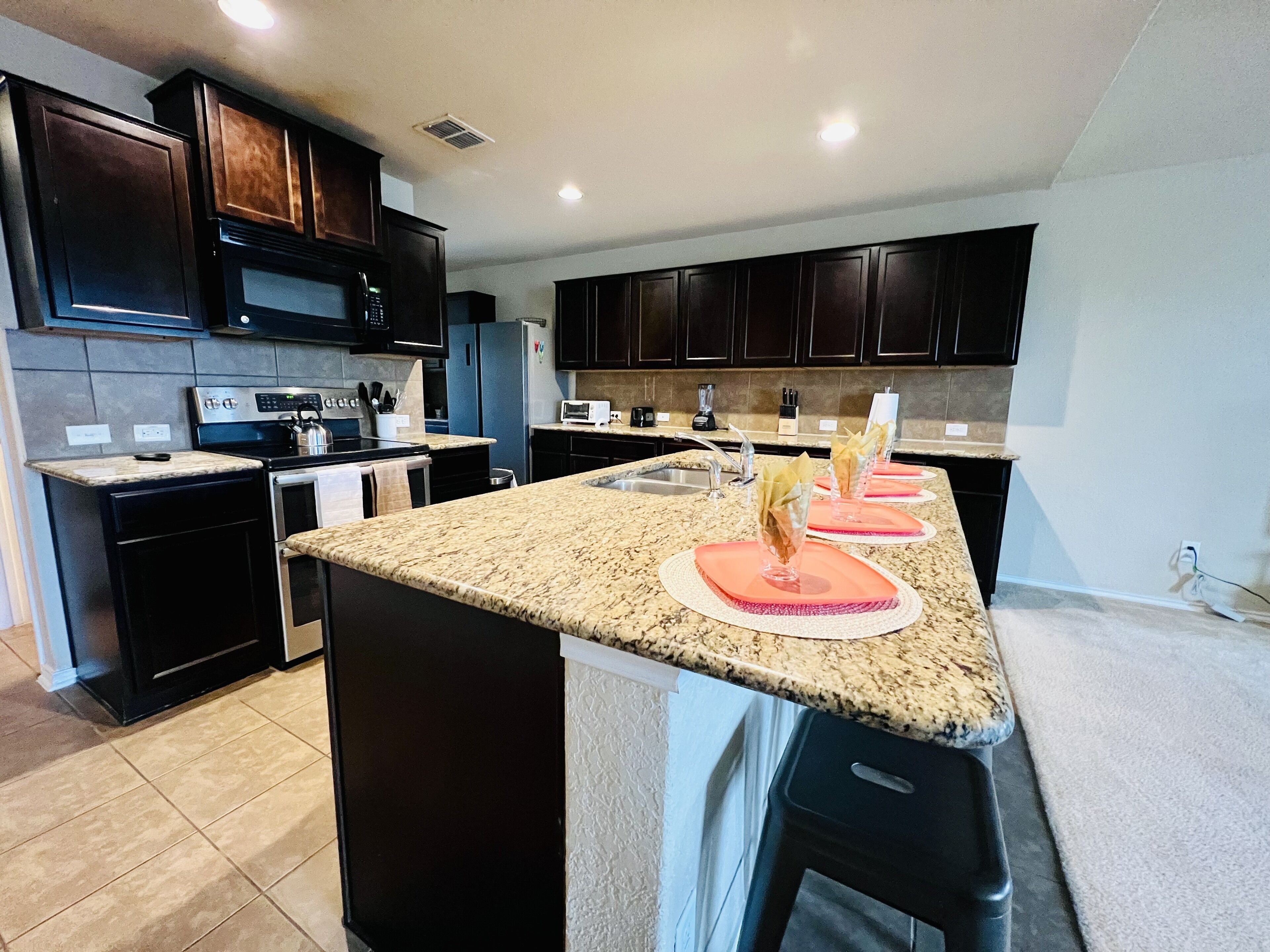 A modern kitchen with dark cabinetry, a granite countertop, and a central island.