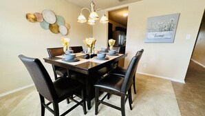 Un coin repas avec une table en bois foncé, dressée pour six personnes, entourée de chaises noires.