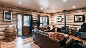 A log cabin interior with a leather sofa, a fireplace, and framed artwork on the walls. - Cuan Den Log Cabin - Base Of Mt Buller - Book Now For School Holidays! (Sawmill Settlement)