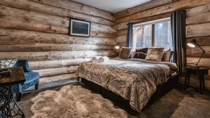 A log cabin bedroom with a bed, a chair, a desk, a lamp, and a window. - Cuan Den Log Cabin - Base Of Mt Buller - Book Now For School Holidays! (Sawmill Settlement)