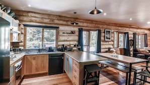 A log cabin interior with a kitchen, dining area, and a view of the outdoors. - Cuan Den Log Cabin - Base Of Mt Buller - Book Now For School Holidays! (Sawmill Settlement)