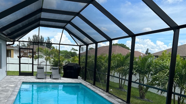 Área de piscina descoberta coberta, com mesa de bilhar e tacos.