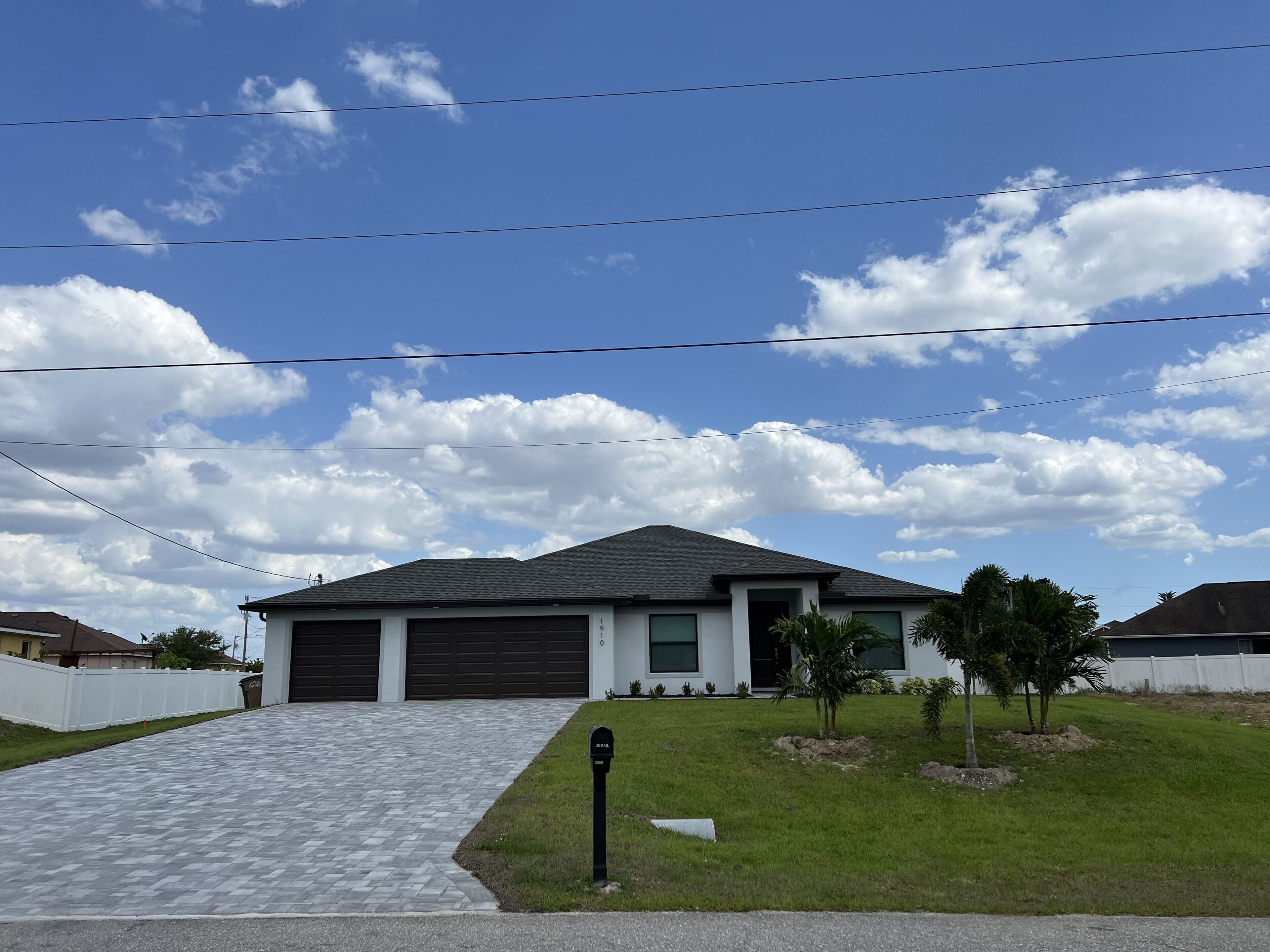 A residential house with a paved driveway, a garage, and a small lawn with a mailbox.