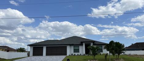 A residential house with a paved driveway, a garage, and a small lawn with a mailbox.
