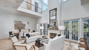 Ein geräumiges Wohnzimmer mit hoher Decke, Kamin und Balkon.