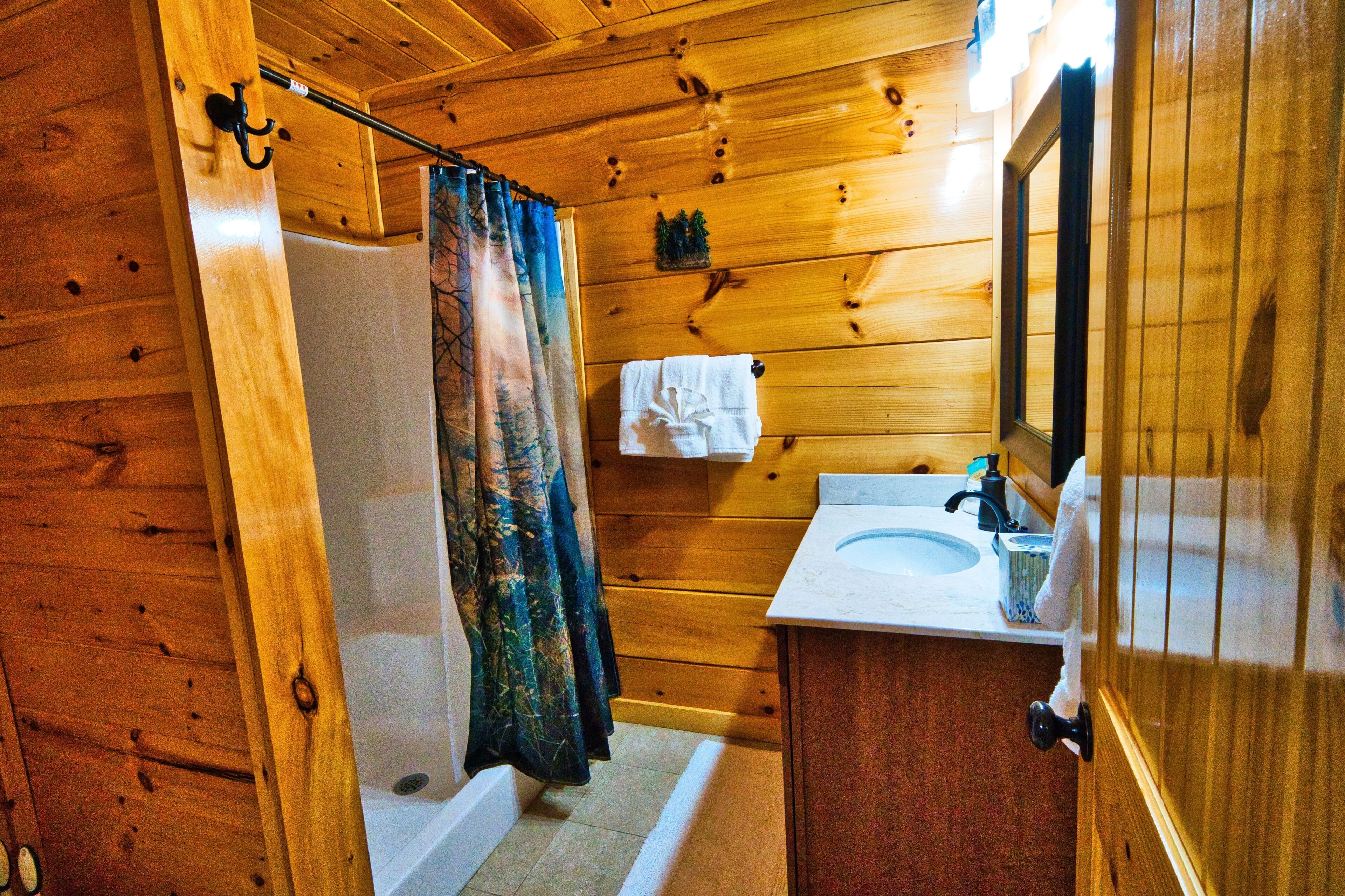 A wooden cabin bathroom with a bathtub, a sink, and a mirror.