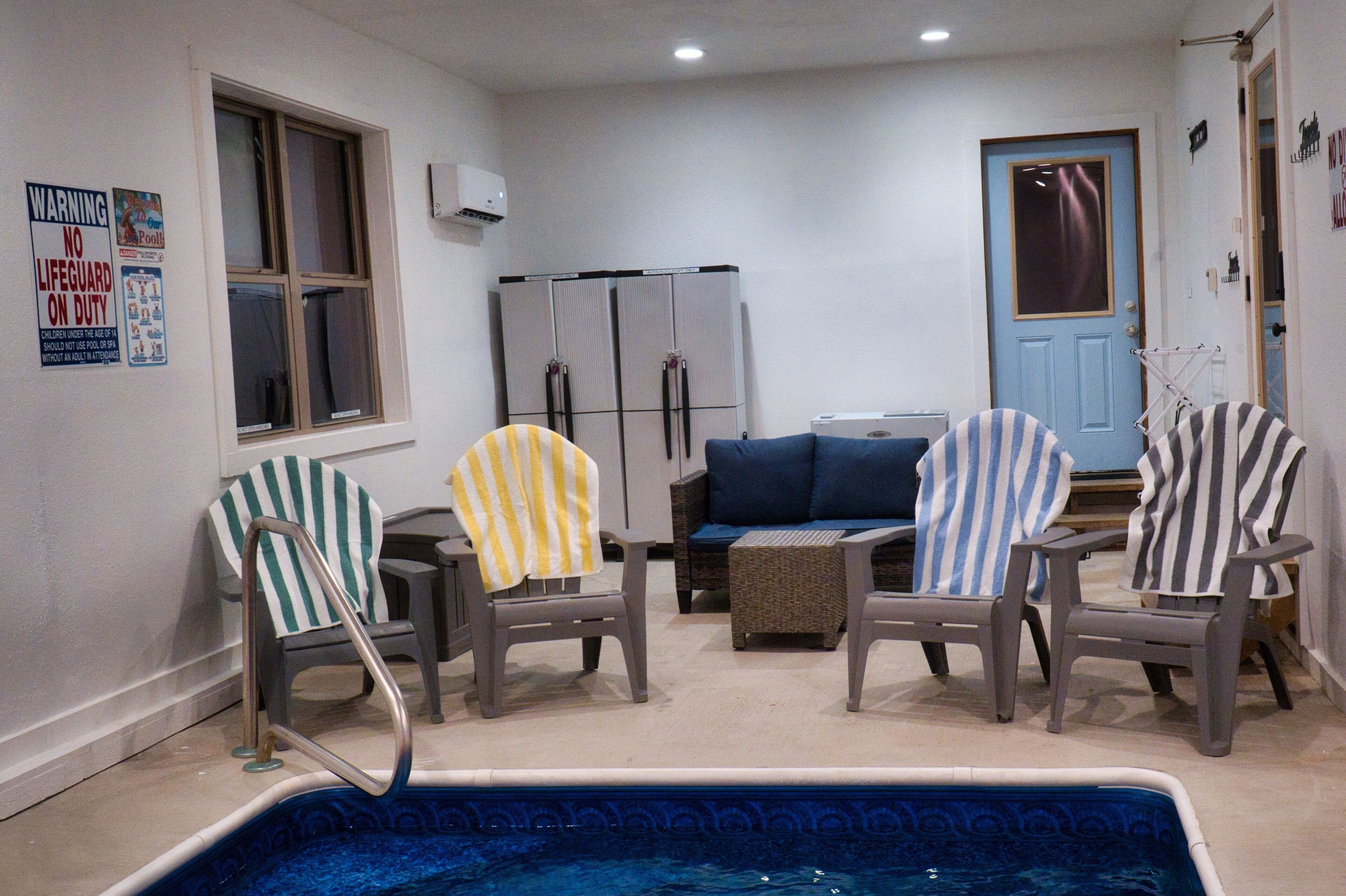 A poolside area with lounge chairs, a pool, and a door.