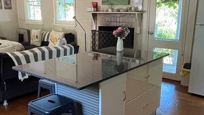 Una cocina moderna con una isla central, taburetes de bar, una chimenea y un área de comedor con sofá.