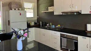 Una cocina moderna con armarios blancos, encimera negra y microondas integrado.