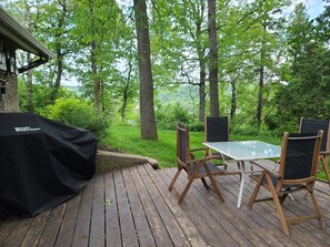 Une terrasse en bois avec une table et des chaises, donnant sur une zone boisée.