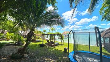 Un espace extérieur de style tropical avec un trampoline, des chaises longues et une zone piscine.