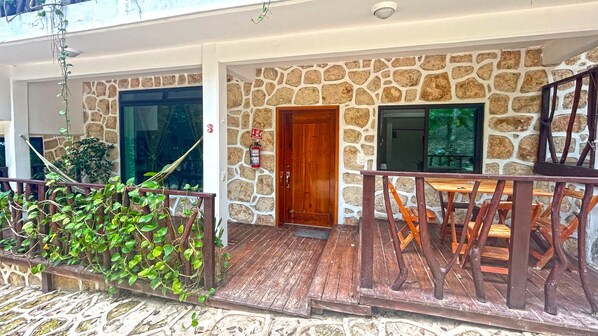 A stone facade with a wooden door, a fire extinguisher, and a wooden railing. - Hotel Wayak Bacalar (Bacalar)