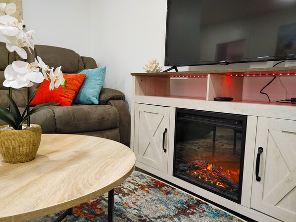 A living room with a sofa, a TV, a fireplace, and a table with a plant.