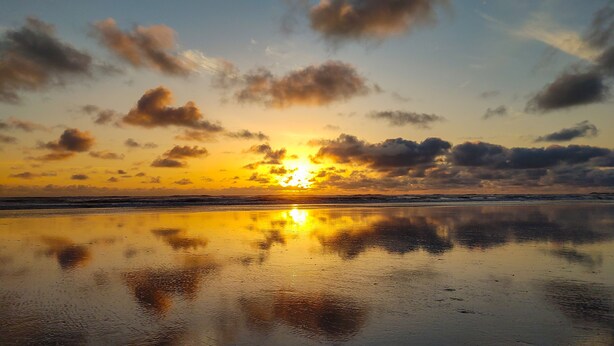A beach with a sunset reflection on wet sand.