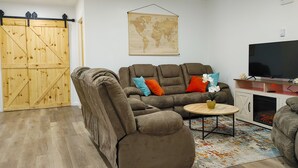A living room with a brown sofa, a small round table, a TV, and a world map on the wall.