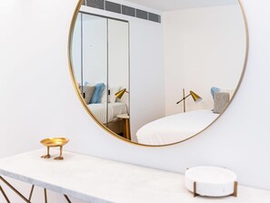 Ein Schlafzimmer mit Bett, Nachttisch, Lampe und Spiegel.